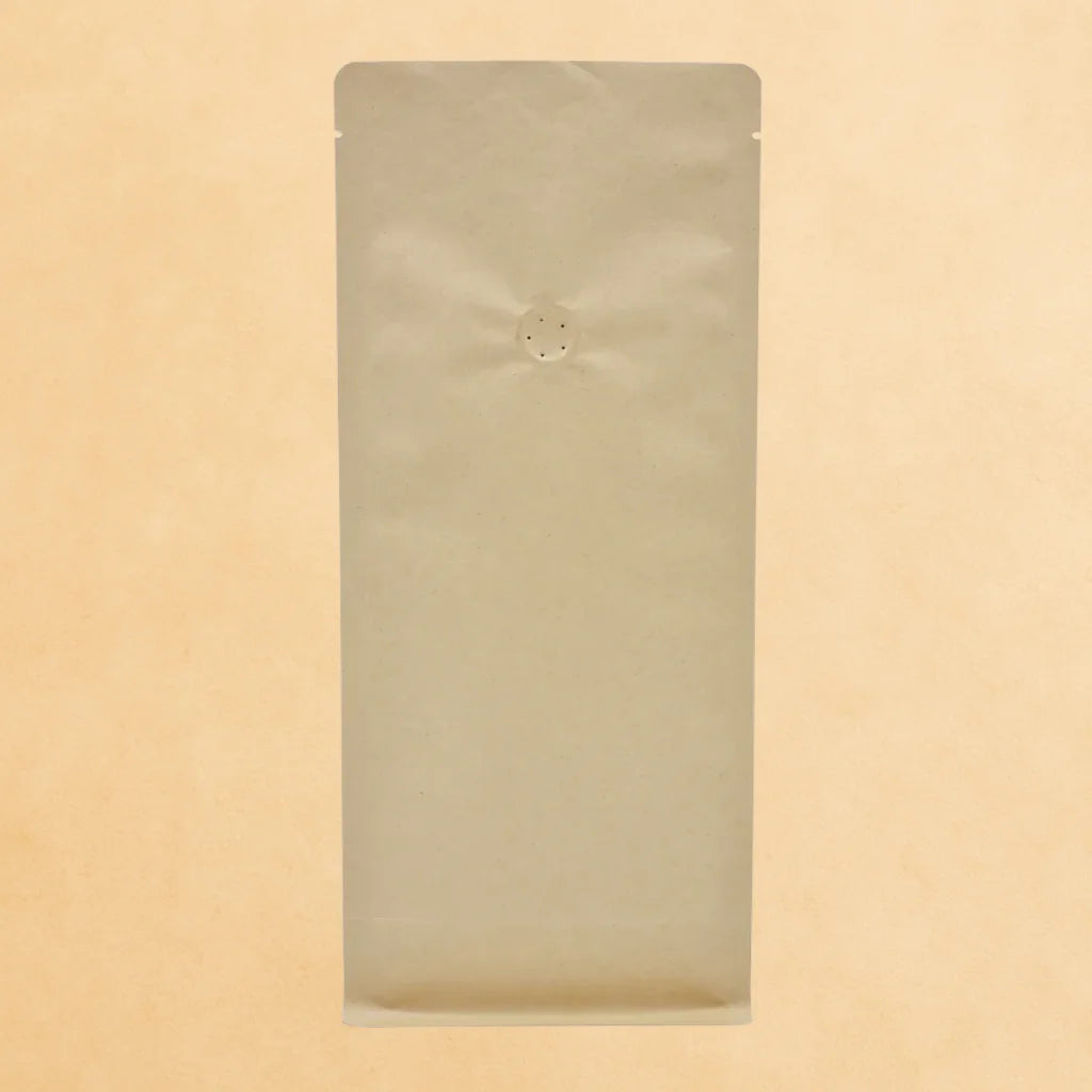 Brown kraft flat bottom coffee bag with one-way valve and open top, displayed upright against a beige background.