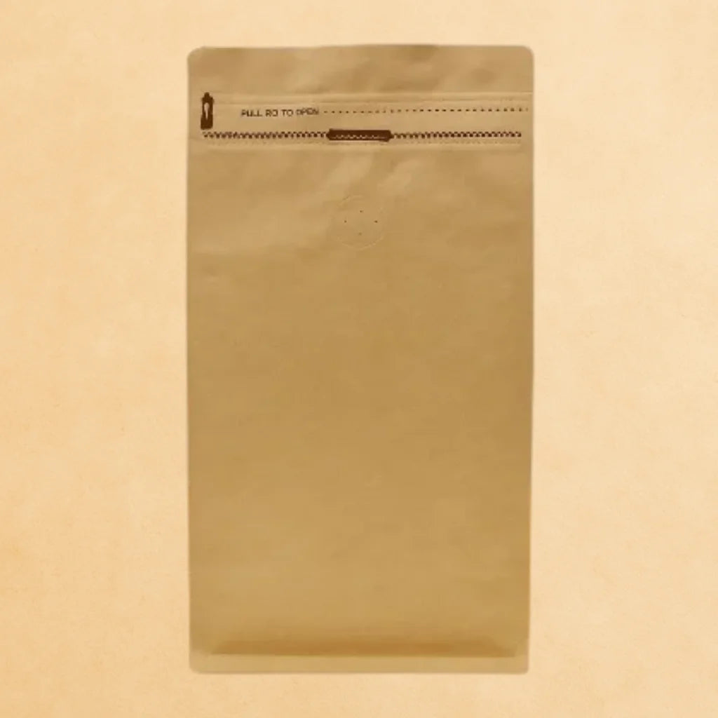 Flat bottom kraft coffee bag with Rip n Zip opening and one-way valve, displayed upright against a beige background.