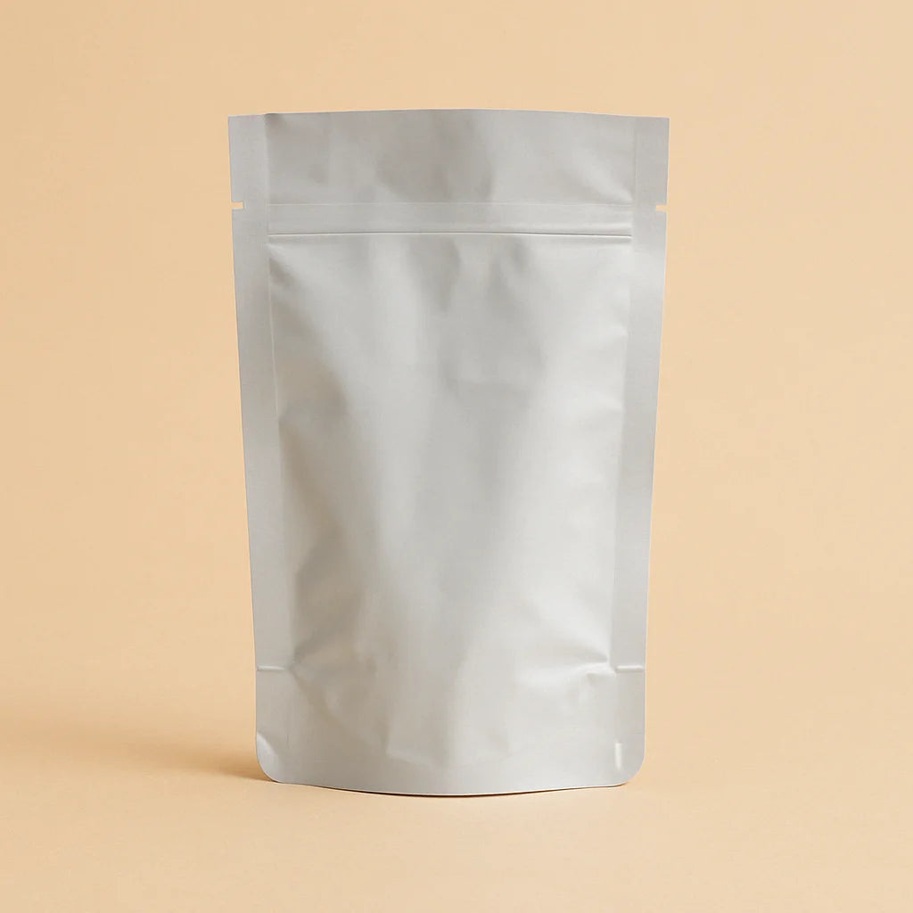 Foil open top stand up pouch displayed empty and upright against a beige background.