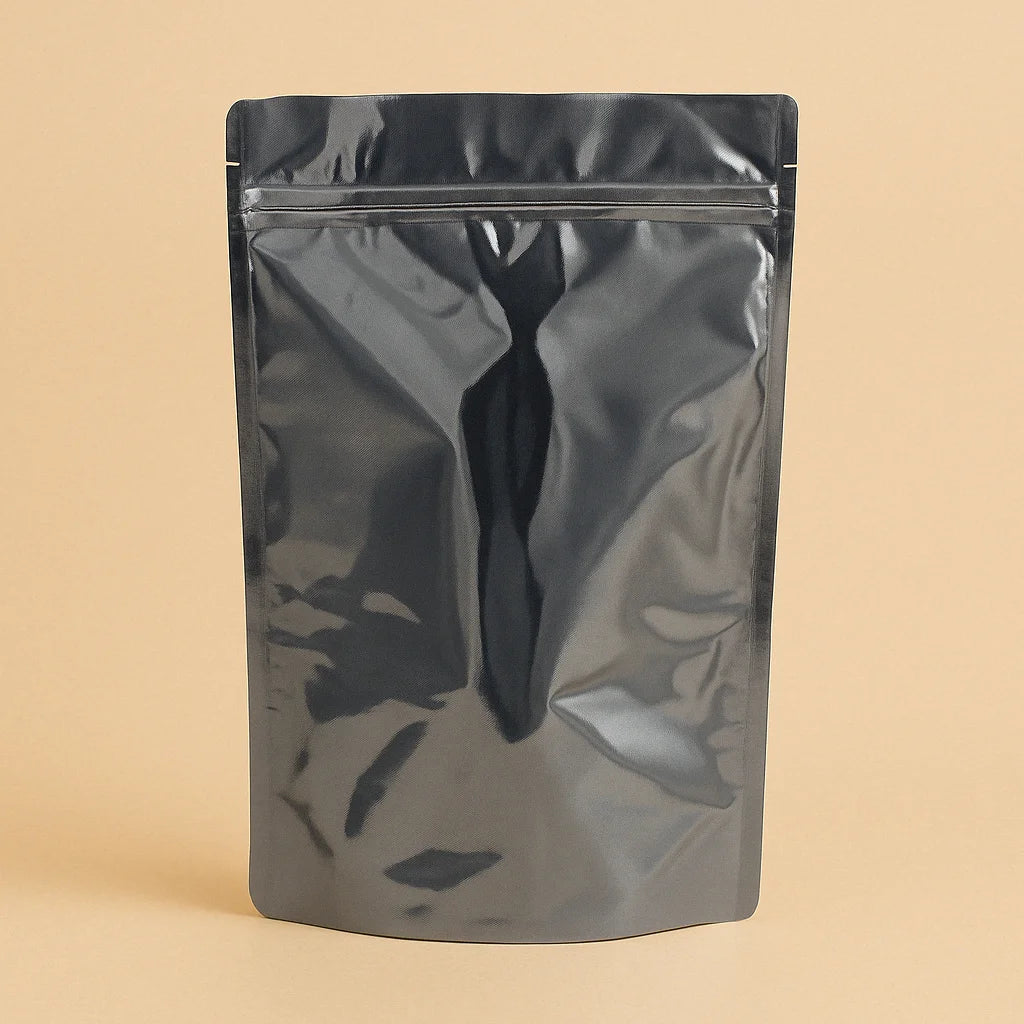 Glossy black sachet pouch with a resealable zipper, shown standing upright against a beige background.