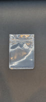Clear resealable sachet pouch with a press-to-close seal, displayed flat and empty against a dark grey background.