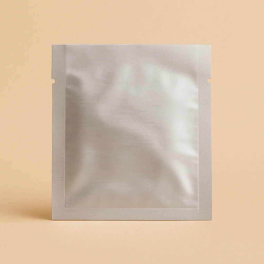 Silver three side seal open top sachet with tear notches, displayed upright against a beige background.