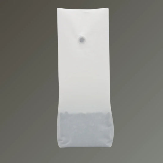 Matt white recyclable coffee pouch with open top and one-way valve, displayed upright against a grey background.