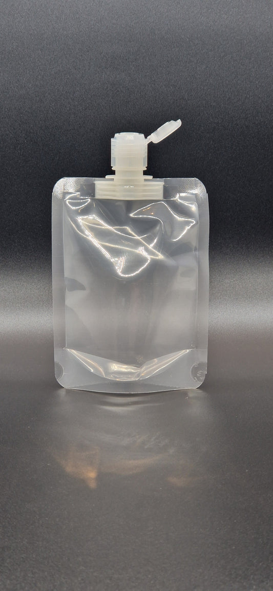 Clear plastic spout pouch with centre spout and flip-top cap, shown upright against a dark gradient background.