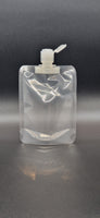Clear plastic spout pouch with centre spout and flip-top cap, shown upright against a dark gradient background.