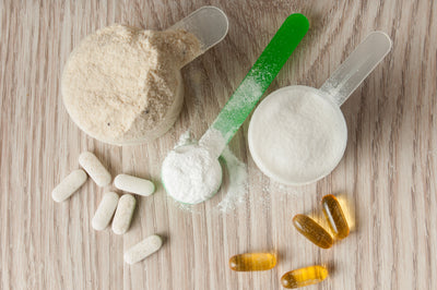 Supplement powders in scoops with capsules on a wooden surface