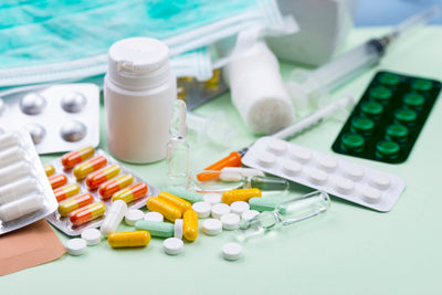Assorted medications including pills, capsules, and bottles on a light green surface.