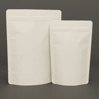 Two white kraft compostable resealable stand up pouches in different sizes, displayed upright against a dark background.