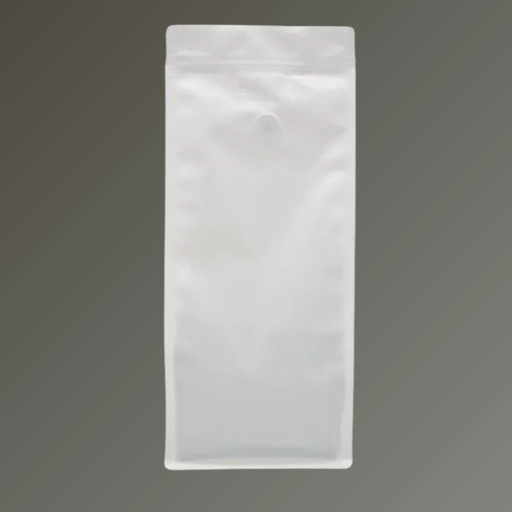 White recyclable coffee pouch with side gussets, resealable zipper and one-way valve, shown upright against a grey background.