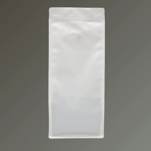 White recyclable coffee pouch with side gussets, resealable zipper and one-way valve, shown upright against a grey background.