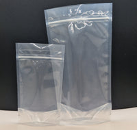 Two clear recyclable resealable stand up pouches of different sizes, displayed empty against a black background.