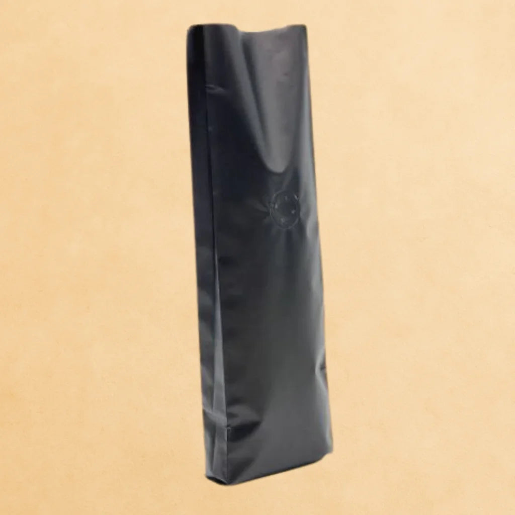 A black open top with a side gusset and degassing valve coffee pouch from the side.