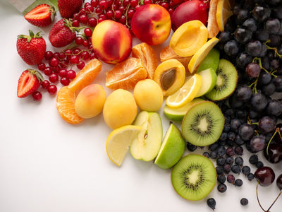 Assorted fruits including strawberries, nectarines, apricots, lemons, kiwis, and grapes on a white background