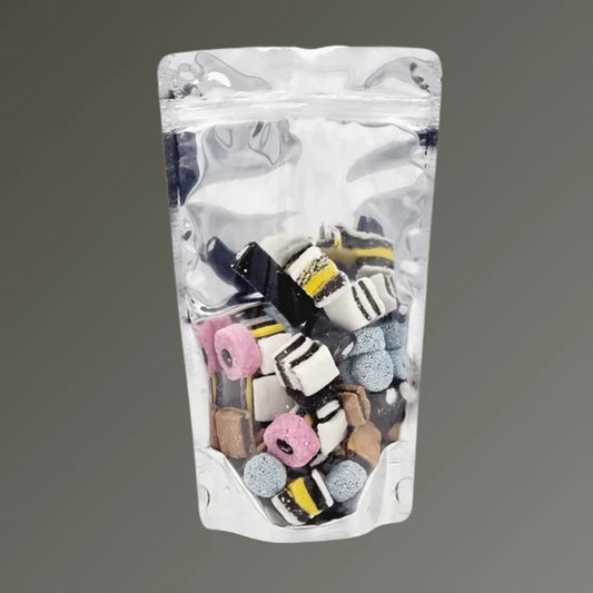 Clear front/chrome back resealable stand up pouch filled with assorted liquorice sweets, displayed upright against a grey background.