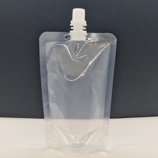 Clear plastic stand up spout pouch with centre spout and white screw cap, shown upright against a dark background.