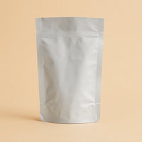 Foil open top stand up pouch displayed empty and upright against a beige background.