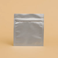 Silver flat pouch with resealable zipper, displayed upright against a beige background, ideal for food or supplement storage.