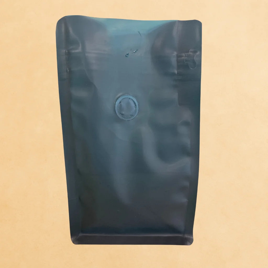 Front view of a green recyclable flat bottom coffee bag with open top and integrated one-way degassing valve, shown against a neutral background.