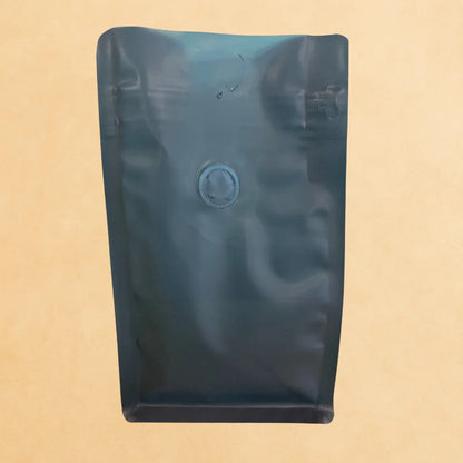 Front view of a green recyclable flat bottom coffee bag with open top and integrated one-way degassing valve, shown against a neutral background.