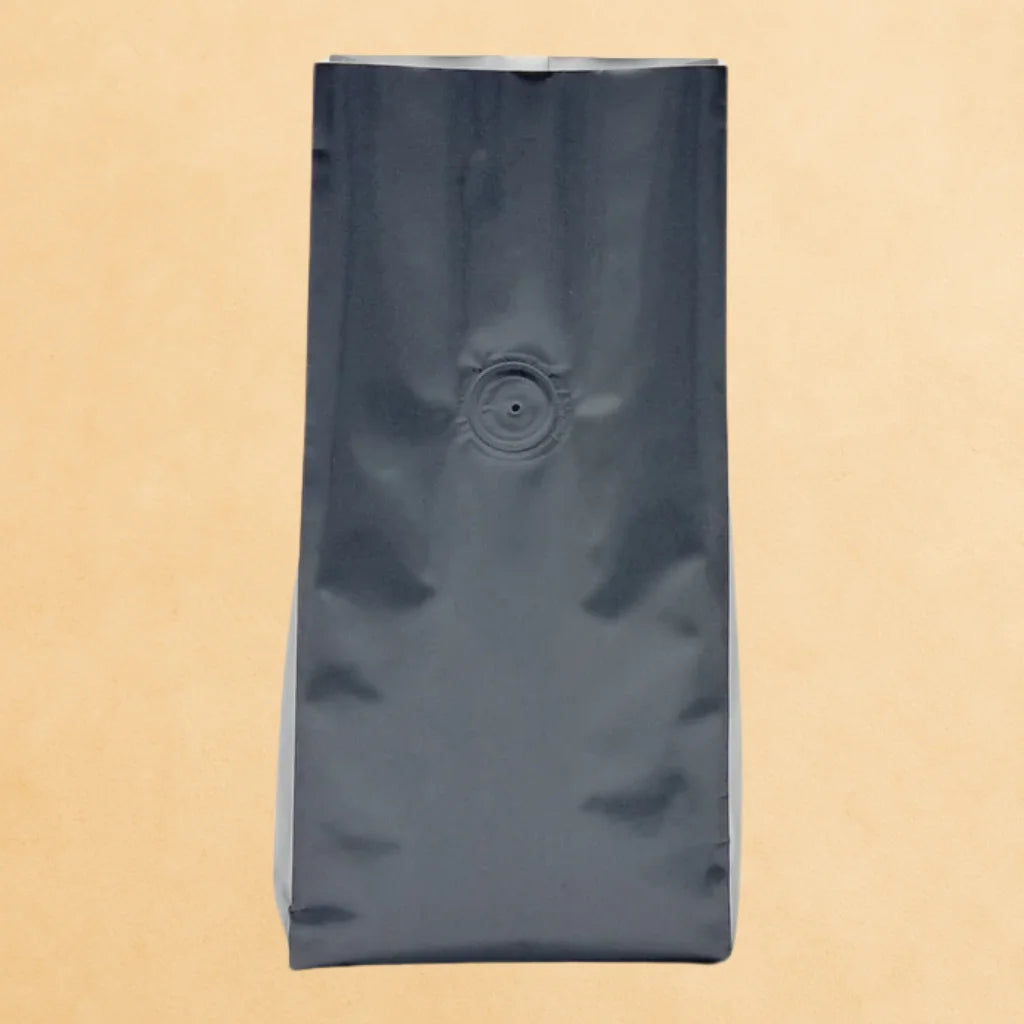 Matt black open top flat bottom coffee pouch with valve, shown upright against a beige background.